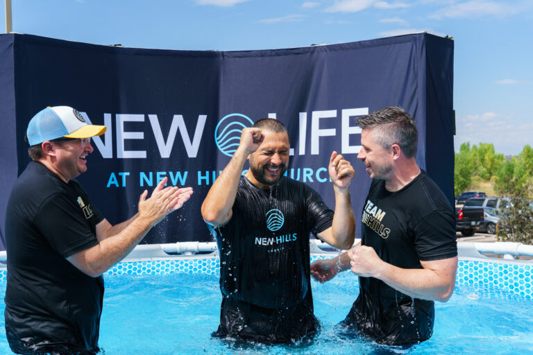 Three men celebrating in the baptism pool at New Hills Church